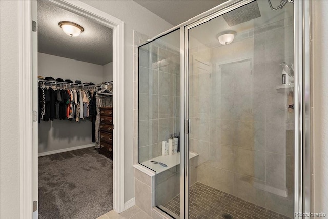 full bathroom featuring a stall shower, baseboards, a textured ceiling, and a walk in closet