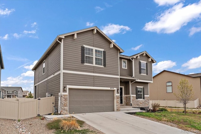 craftsman house featuring stone siding, driveway, an attached garage, and fence