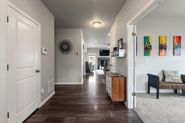 hallway with baseboards, dark wood-style flooring, and visible vents