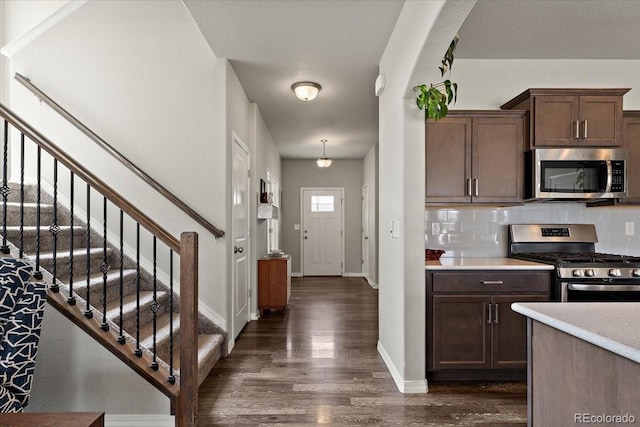 kitchen featuring stainless steel appliances, dark wood finished floors, baseboards, light countertops, and tasteful backsplash