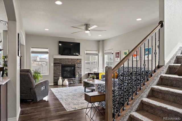 living room with a fireplace, ceiling fan, stairs, and wood finished floors