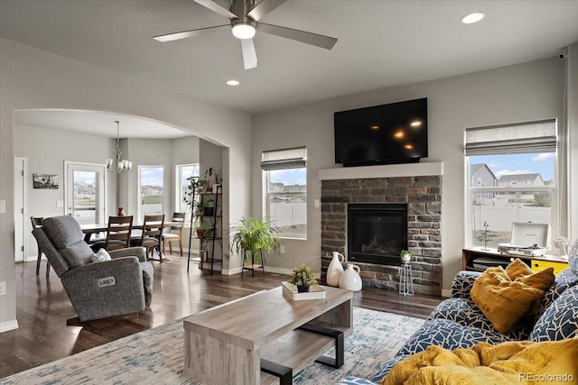 living area featuring arched walkways, wood finished floors, plenty of natural light, and ceiling fan with notable chandelier