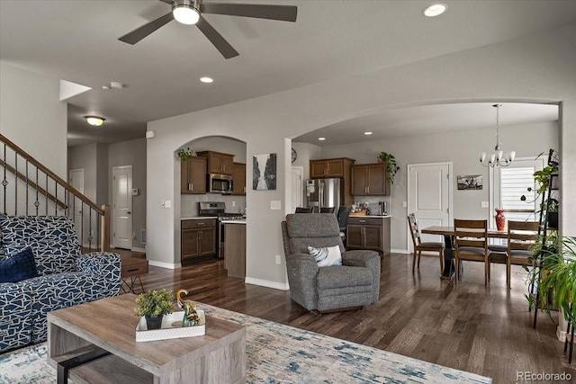 living room featuring arched walkways, recessed lighting, dark wood-style floors, and ceiling fan with notable chandelier