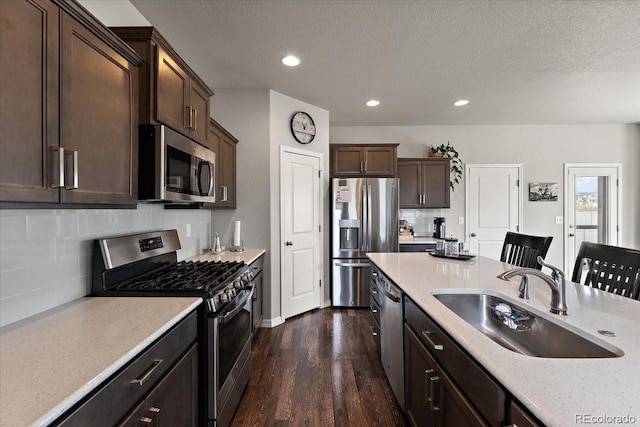 kitchen with light countertops, stainless steel appliances, dark wood-style floors, and a sink