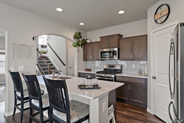 kitchen featuring dark wood-style floors, appliances with stainless steel finishes, a sink, and dark brown cabinetry