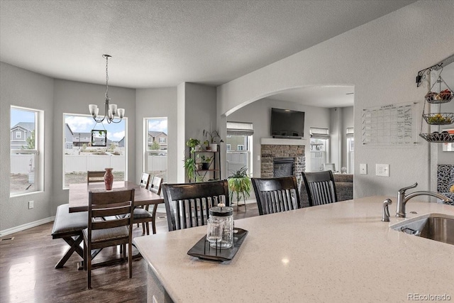 dining room with baseboards, a wealth of natural light, a fireplace, and dark wood-style floors