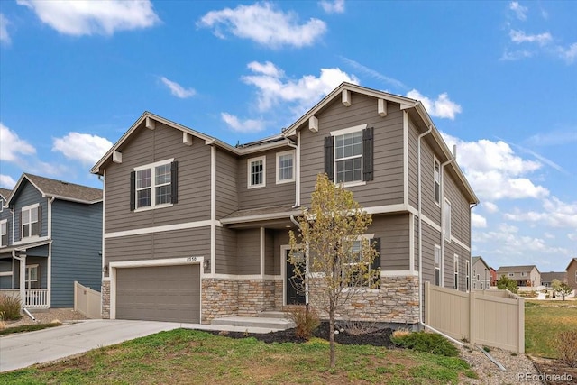 craftsman-style home with stone siding, driveway, an attached garage, and fence