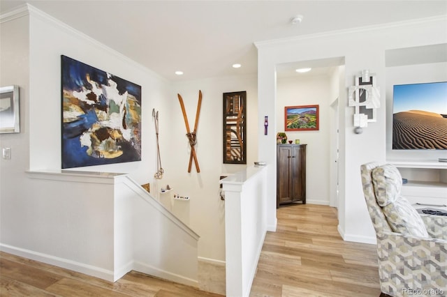 hall featuring crown molding, light wood-style floors, recessed lighting, baseboards, and an upstairs landing