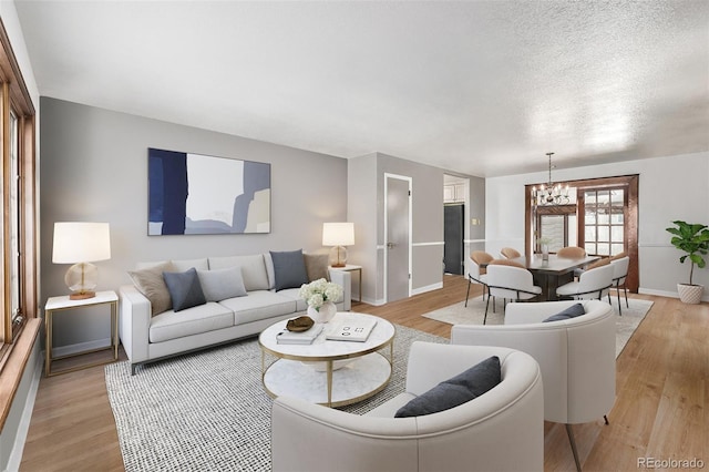 living room with an inviting chandelier, light hardwood / wood-style floors, and a textured ceiling