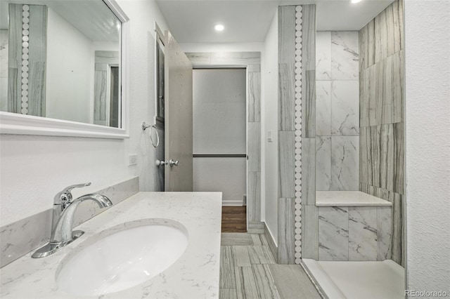 bathroom featuring a tile shower and vanity