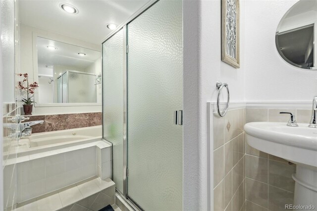 bathroom featuring plus walk in shower and tile walls