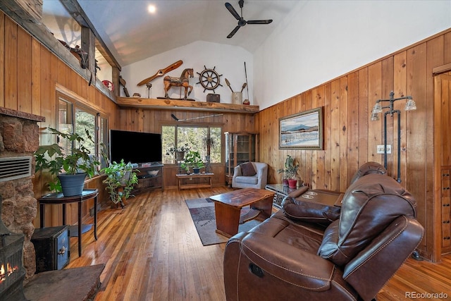 living area with hardwood / wood-style floors, wooden walls, ceiling fan, and high vaulted ceiling