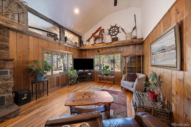 living area featuring wooden walls, a healthy amount of sunlight, and light wood finished floors