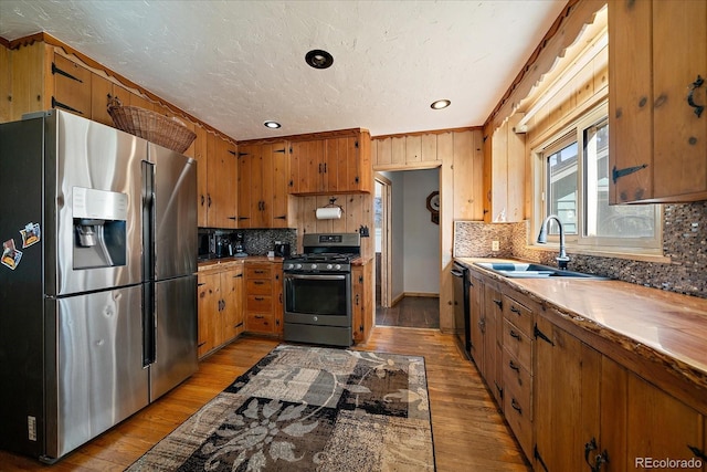 kitchen featuring brown cabinets, appliances with stainless steel finishes, light wood-style floors, and a sink