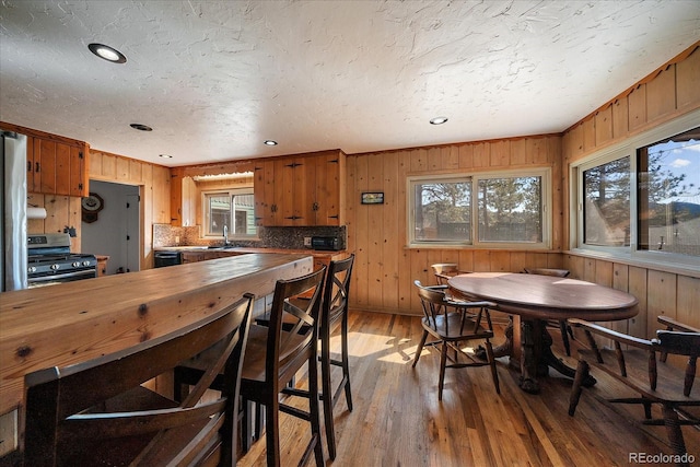 dining room with wooden walls, light wood finished floors, and a textured ceiling