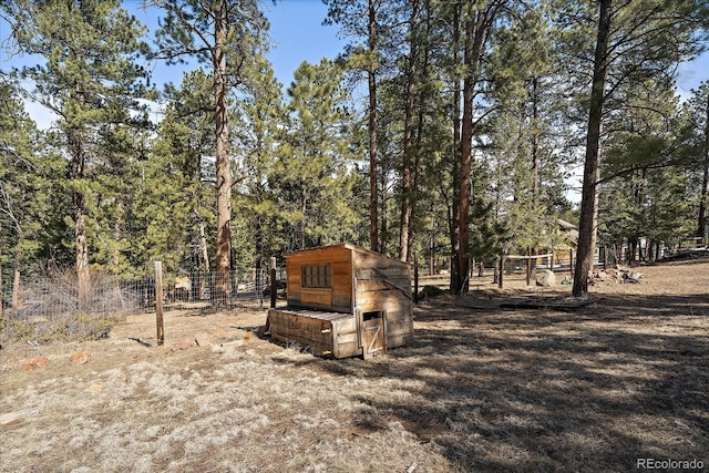 view of yard featuring exterior structure, an outdoor structure, and fence