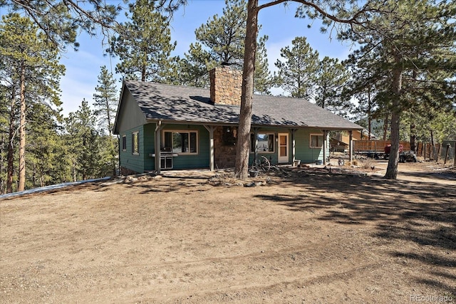 view of front of property with a shingled roof, a chimney, and fence