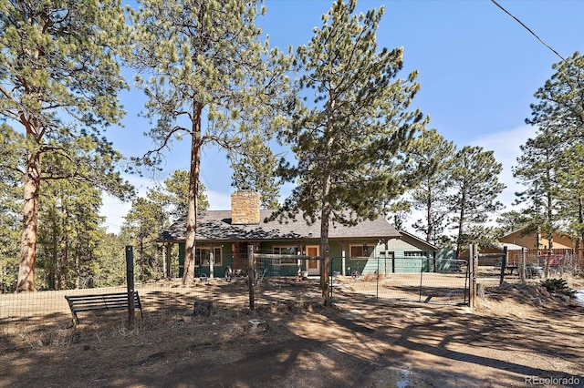 back of house with a gate, a chimney, and fence