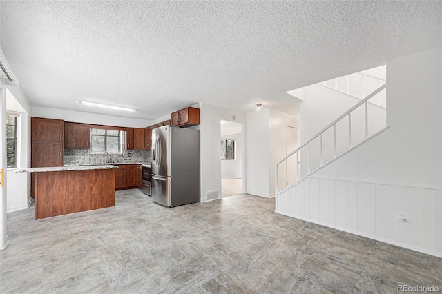 14190 E Gunnison Pl, Aurora, CO 80012 - kitchen featuring stainless steel appliances, open floor plan, a textured ceiling, a kitchen island, and tasteful backsplash