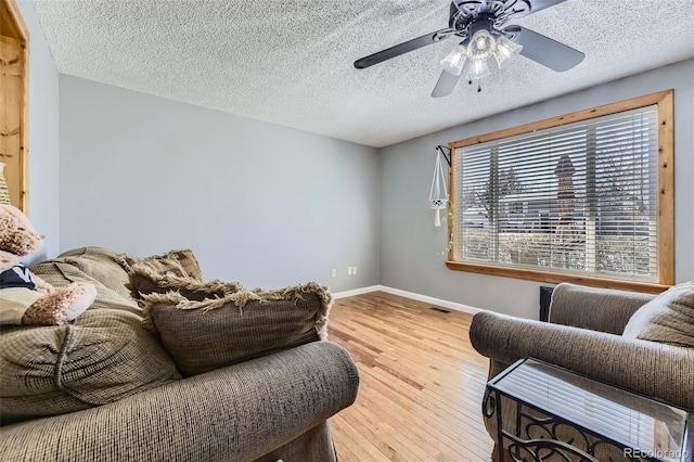 living room with visible vents, baseboards, ceiling fan, a textured ceiling, and wood-type flooring
