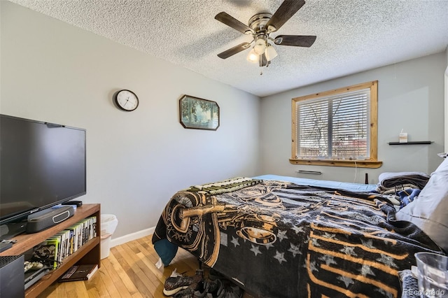 bedroom with baseboards, a ceiling fan, wood finished floors, and a textured ceiling