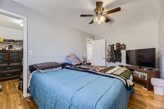 bedroom with light wood-style flooring, a ceiling fan, and a textured ceiling