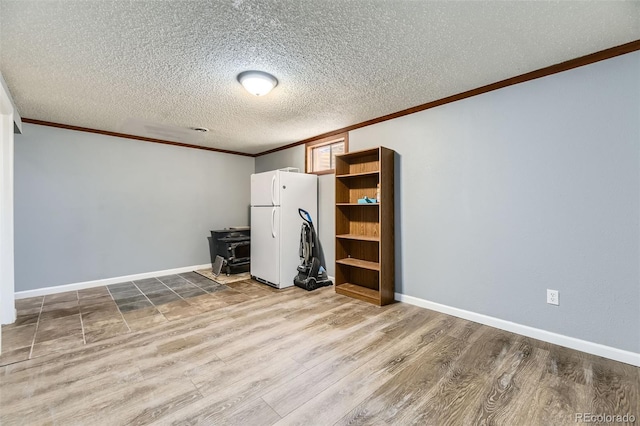 empty room featuring crown molding, baseboards, wood finished floors, and a textured ceiling
