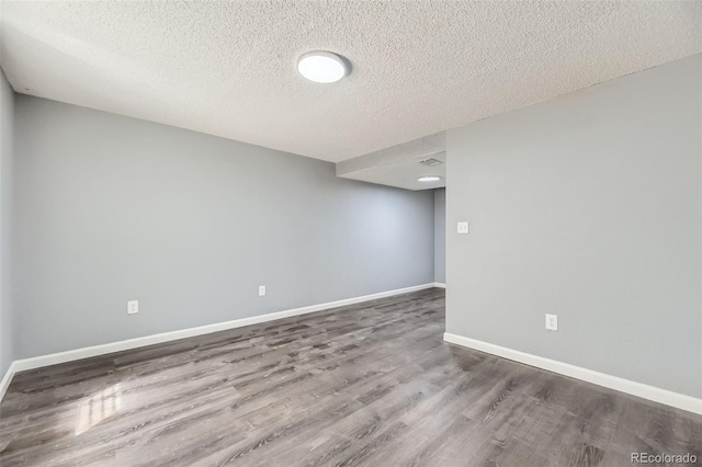 empty room featuring baseboards, wood finished floors, and a textured ceiling