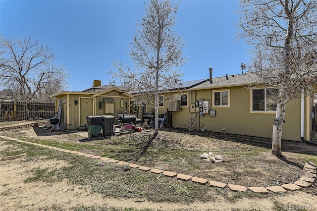 back of property featuring fence and solar panels