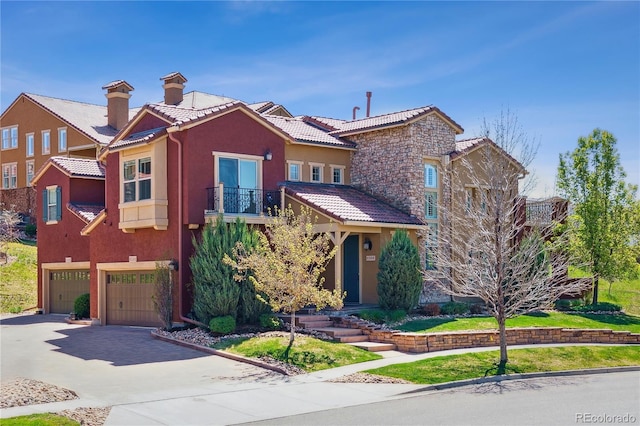 view of front facade with a balcony, stucco siding, a tiled roof, and an attached garage