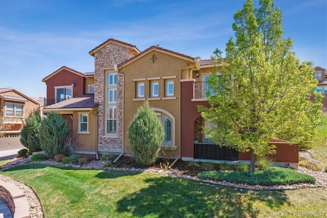 view of front of property featuring a balcony, a front yard, stucco siding, and stone siding