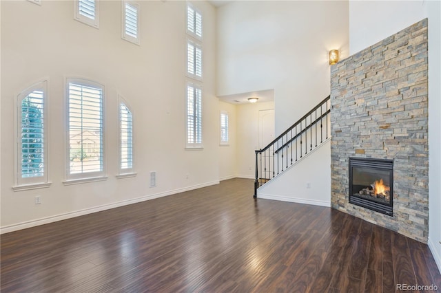 unfurnished living room featuring a wealth of natural light, dark wood-style flooring, and a fireplace