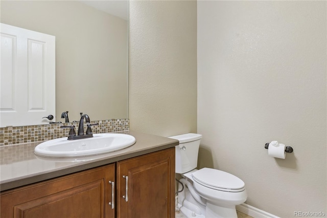 bathroom with vanity, toilet, backsplash, and baseboards