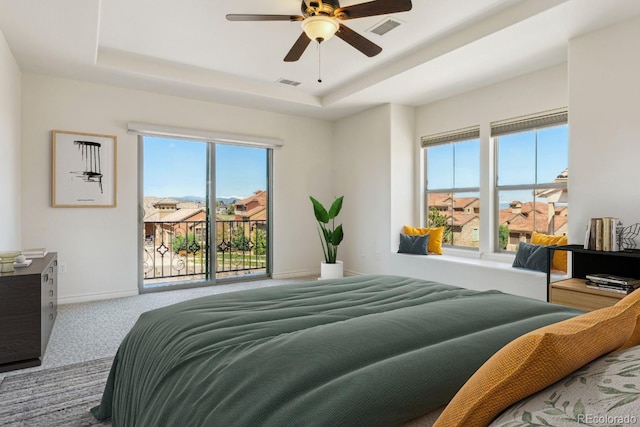 bedroom featuring a tray ceiling, visible vents, multiple windows, and access to exterior