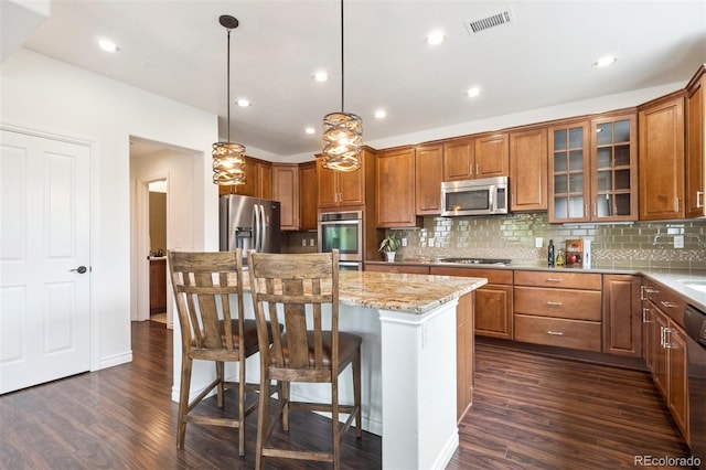 9588 Firenze Way, Highlands Ranch, CO 80126 - kitchen featuring stainless steel appliances, dark wood finished floors, a breakfast bar, a center island, and recessed lighting
