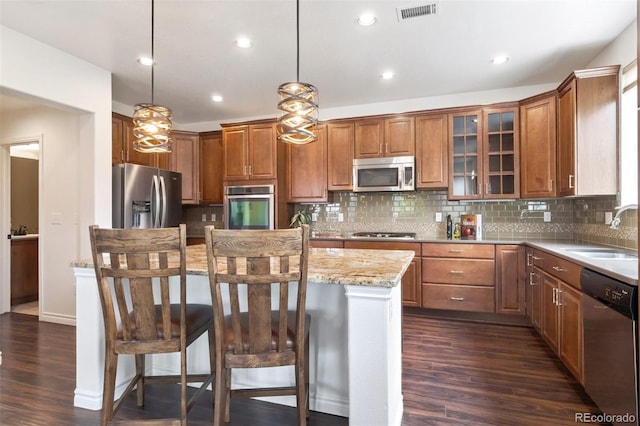 9588 Firenze Way, Highlands Ranch, CO 80126 - kitchen with appliances with stainless steel finishes, a center island, a kitchen bar, backsplash, and recessed lighting