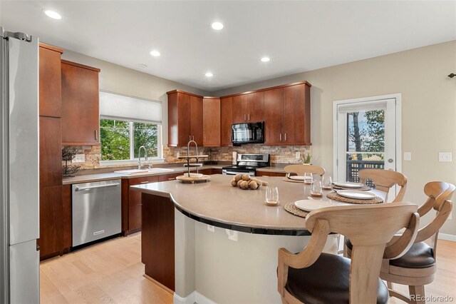 22 Apache Plume St, Brighton, CO 80601 - kitchen featuring appliances with stainless steel finishes, light wood-type flooring, tasteful backsplash, a breakfast bar, and recessed lighting