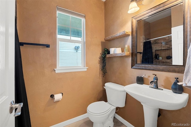 22 Apache Plume St, Brighton, CO 80601 - bathroom with toilet, baseboards, a shower with shower curtain, and a sink
