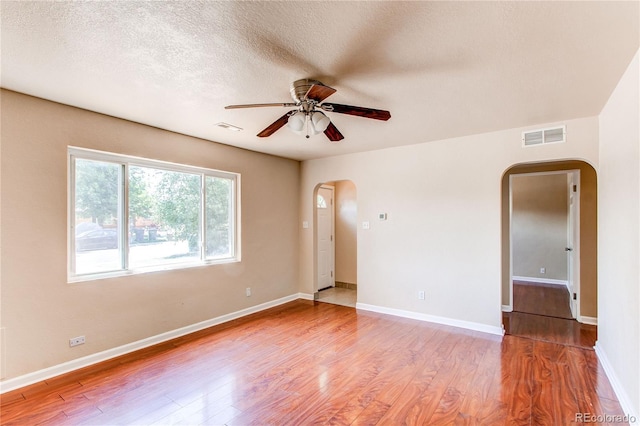 9150 Lilly Ct, Thornton, CO 80229 - empty room featuring arched walkways, a ceiling fan, wood finished floors, and a textured ceiling