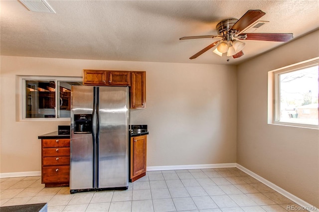 9150 Lilly Ct, Thornton, CO 80229 - kitchen featuring stainless steel fridge, brown cabinetry, a ceiling fan, dark countertops, and light tile patterned floors