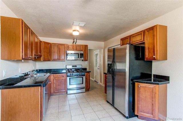 9150 Lilly Ct, Thornton, CO 80229 - kitchen featuring stainless steel appliances, brown cabinets, light tile patterned floors, a textured ceiling, and tile counters
