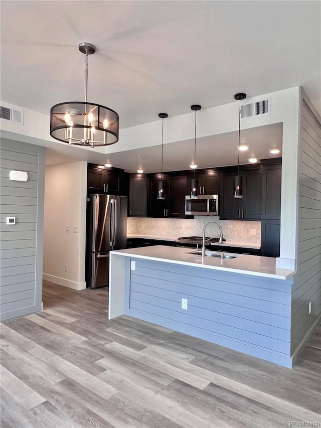 kitchen with appliances with stainless steel finishes, a chandelier, sink, and light hardwood / wood-style floors