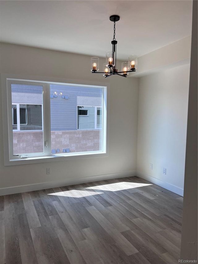 spare room featuring hardwood / wood-style flooring and a chandelier