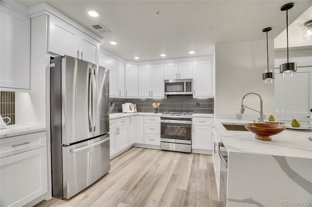 kitchen with light hardwood / wood-style flooring, decorative light fixtures, light stone countertops, stainless steel appliances, and sink