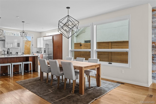 dining room featuring a notable chandelier, light wood-style flooring, visible vents, and baseboards