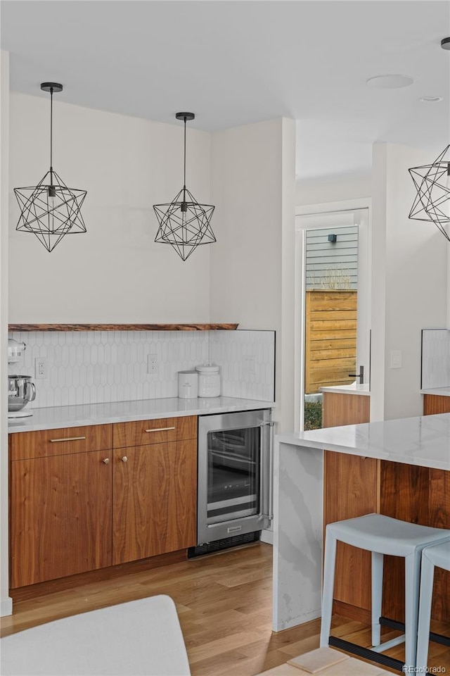 bar featuring beverage cooler, light wood finished floors, and decorative light fixtures