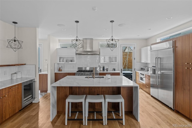 kitchen featuring wall chimney range hood, modern cabinets, wine cooler, and appliances with stainless steel finishes