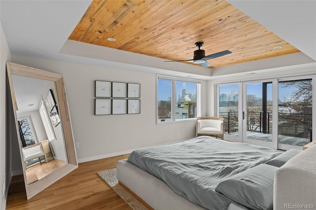 bedroom with wooden ceiling, access to outside, a raised ceiling, and wood finished floors