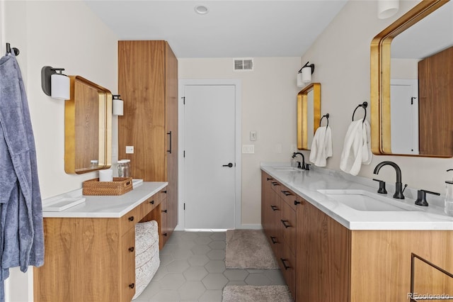 bathroom with double vanity, visible vents, a sink, and tile patterned floors