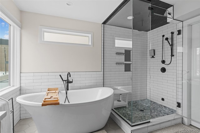 bathroom featuring a soaking tub, a shower stall, and tile walls